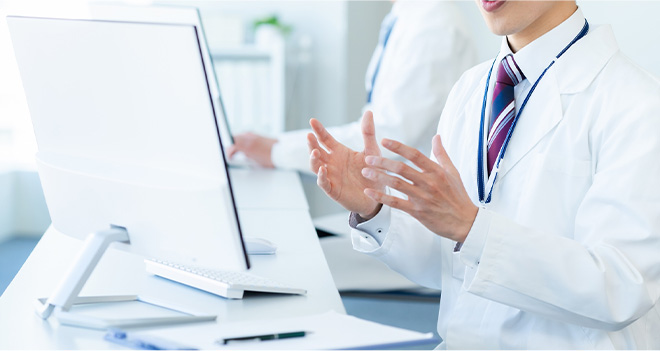 PC画面に向かい診療案内をするドクター
